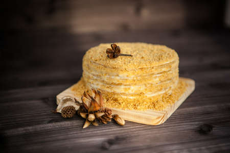 homemade honey cake decorated with golden wooden flowers on dark background