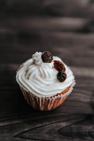 muffin with cream and raisins on a dark wooden backgroundの写真素材