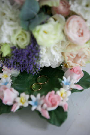 wedding bouquet of the bride in light colors with pink roses, white eustoma with the addition of eucalyptus and wedding rings on a green backgroundの写真素材