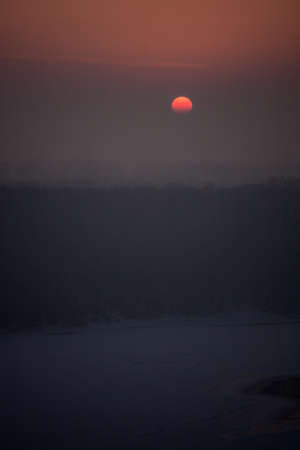 the red sun sets in a gray-pink haze. winter pastel landscape. honey sunsetの写真素材