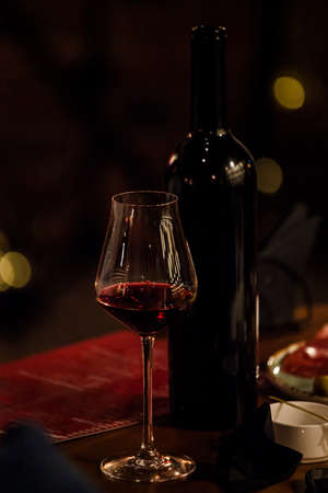 wine glasses and bottles of wine in the entourage of the wine bar in the eveningの写真素材