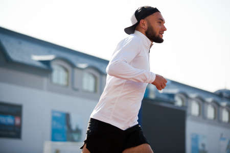 a white man in black shorts and white running at the stadium. workoutの写真素材
