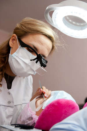 A girl makes the procedure for extending eyelashes during a pandemic, a master with tools in his handsの写真素材