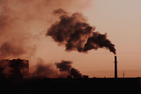 steam from the boiler room pipes in the contoured light of dawn, urban landscape. Smoke from the brick chimney of the plant in the early morning.の写真素材