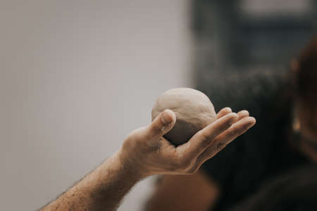 Man holds a ball of dough in his hands. Close-up.