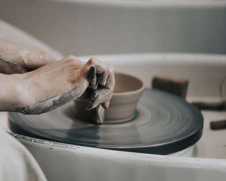 Master class on modeling of clay on a potter's wheel. work in a pottery workshop. close-up of hands and potter's wheelの写真素材