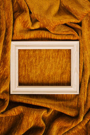 Creative concept of white wood frame against golden yellow fabric cloth wave background. Minimal design with copy space.の写真素材