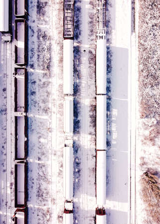 Top view of cargo trains. Aerial view from flying drone of snow covered freight trains on the railway station. Wagons with goods on railroad with on man the middle. Heavy industry. Industrial conceptual scene with trains.の写真素材