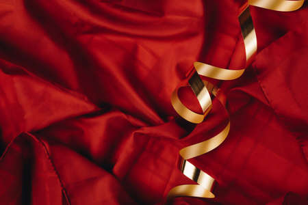 Abstract concept art of red silk or saten background with golden ribbon. Party or birthday idea with copy space.の写真素材