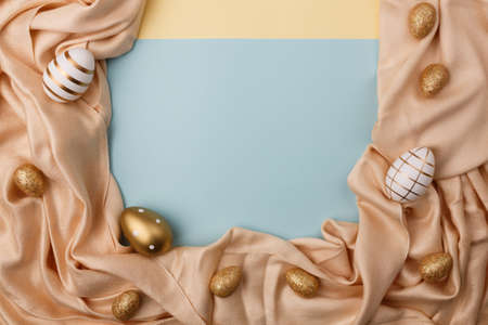 Minimal concept palm leaves with a golden easter eggs on a silk or satin fabric against pastel background with copy space.の写真素材