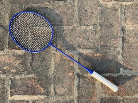 Racket for playing badminton on a rough brick background with evening lighting and shadows.の写真素材