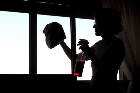 Woman's silhouette cleaning the glasses of a window.の写真素材