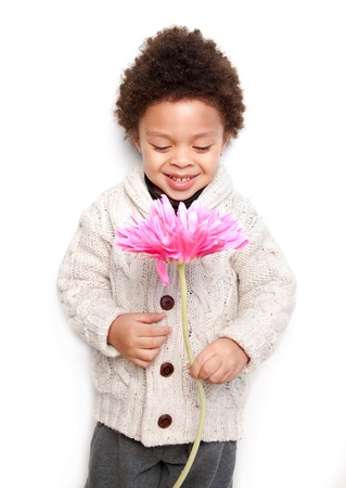 Cute child holding a big pink flower and looking at it isolated on white background の写真素材