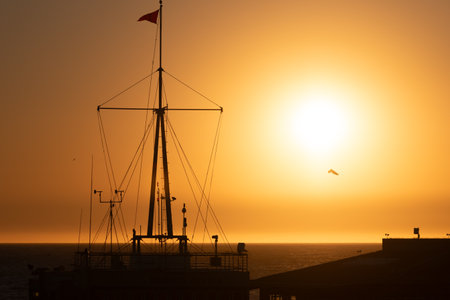 closeup of a pier at sunset with some birds flyingの写真素材