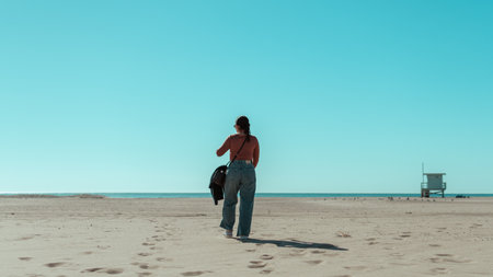 girl with sunglasses walking on the beach sand looking at the seaの写真素材
