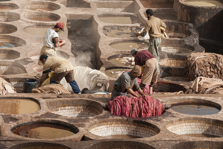 FEZ, MOROCCO - FEBRUARY 20, 2017: Men working within the paint holes at the famous Chouara Tannery in the medina of Fez. The leather tannery dates back to the 11th century AD. The medina is the oldest walled part of Fez.のeditorial素材