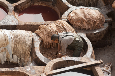 FEZ, MOROCCO - FEBRUARY 20, 2017: Man working inside the paint holes at the famous Chouara Tannery in the medina of Fez. The leather tannery dates back to the 11th century AD. The medina is the oldest walled part of Fez.のeditorial素材