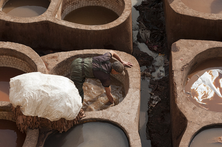 FEZ, MOROCCO - FEBRUARY 20, 2017: Man working inside the paint holes at the famous Chouara Tannery in the medina of Fez. The leather tannery dates back to the 11th century AD. The medina is the oldest walled part of Fez.のeditorial素材