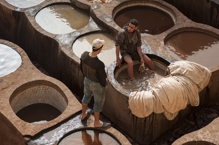FEZ, MOROCCO - FEBRUARY 20, 2017: Men working within the paint holes at the famous Chouara Tannery in the medina of Fez. The leather tannery dates back to the 11th century AD. The medina is the oldest walled part of Fez.のeditorial素材
