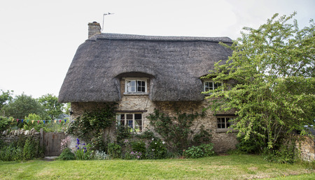 Narrow lane with romantic thatched houses and stone cottages in the lovely Minster Lovell village, Cotswolds, Oxfordshire, Englandのeditorial素材