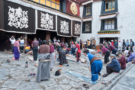 LHASA, TIBET, CHINA - AUGUST, 17 2018: Pilgrims praying worshipping in front of Jokhang temple. The Buddhist Temple in Barkhor Square is considered the most sacred and important temple in Tibet.のeditorial素材