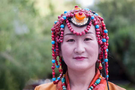 LHASA, TIBET, CHINA - AUGUST, 17 2018: Unidentified Chinese model with Tibetan jewelry in front of...