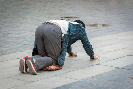 LHASA, TIBET, CHINA - AUGUST, 17 2018: Tibetan pilgrim lying on the floor after prostrating herself. Doing the "Barkhor Kora", a devotional pilgrim circuit around the exterior of old Jokhang Templeのeditorial素材