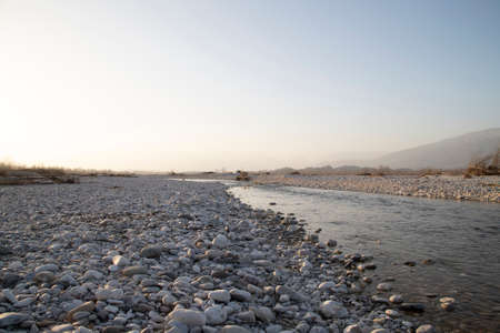 River water with gray pebbles in a sunny dayの写真素材