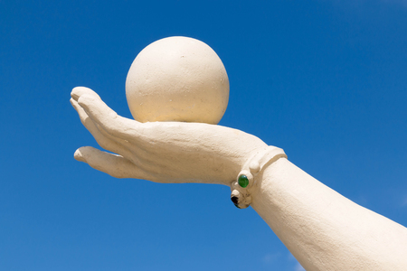ball on hand made of stone on blue skyの写真素材