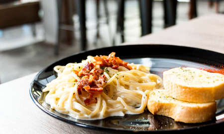 traditional spaghetti carbonara on black plate in restaurantの写真素材