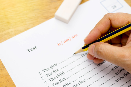 hand holding pencil over english test represent taking examinationの写真素材