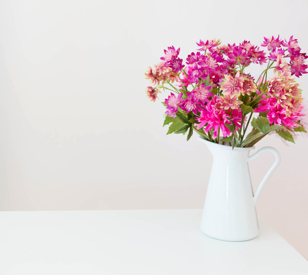imitated pink flowers in white vase on white tableの写真素材