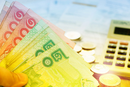 green and red thai banknotes over blur bills and calculator