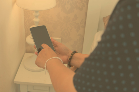 hand holding smart phone in hotel roomの写真素材