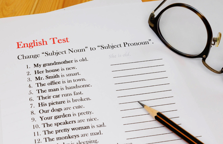 English test sheet on wooden desk represent school test in classroomの写真素材