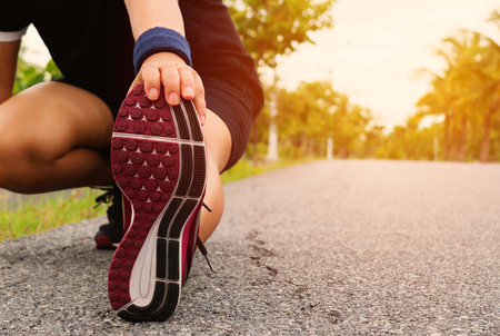 girl stretching her leg on ground in parkの写真素材