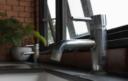 dirty faucet over the sink by the window in bathroomの写真素材