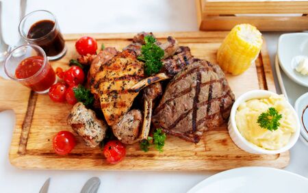 top view of mixed meat steak on wooden plate in restaurant