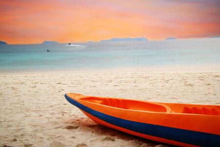 orange kayak boat on beach by blue sea under orange sky