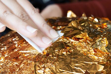 hand of buddhist gilding gold leaflet on golden ball in temple to worship buddha