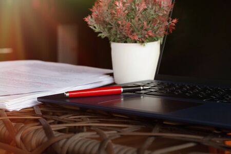 pen on laptop on table with blurred paperwork represent working environmentの写真素材