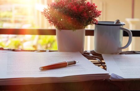 red pen on blurred paperwork on table nearby window 