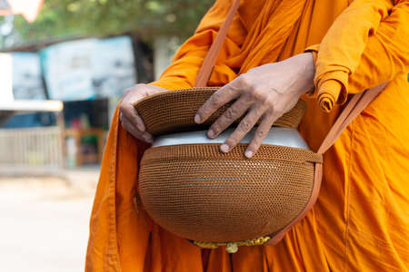 close up buddhist monk hand holding alms bowl to alms round in the morningの写真素材