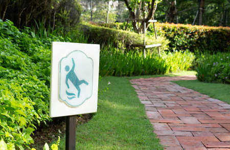 slippery sign beside walkway in garden in morning to warn for cautionの写真素材