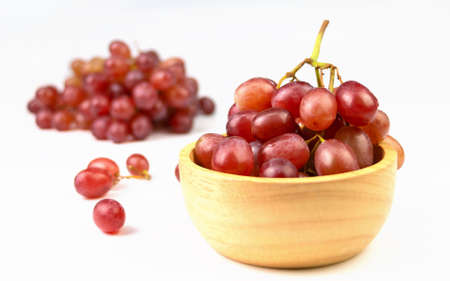 red grapes in wooden cup on white backgroundの写真素材
