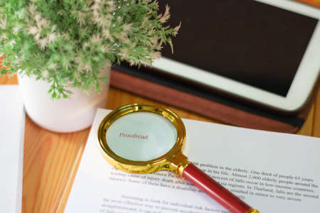 Nakhon Ratchasima, THAILAND-November 11, 2020: close up new golden maginifier on proofreading paper on wooden table with office supplyのeditorial素材
