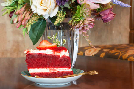 a slice of red strawberry velvel cheese cake on wooden table in vintage coffee shop