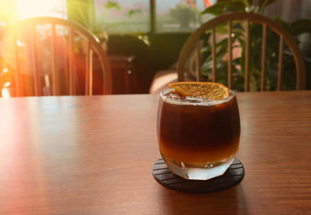 glass of cold black orange coffee on wooden table in cafe in summer with copy spaceの写真素材