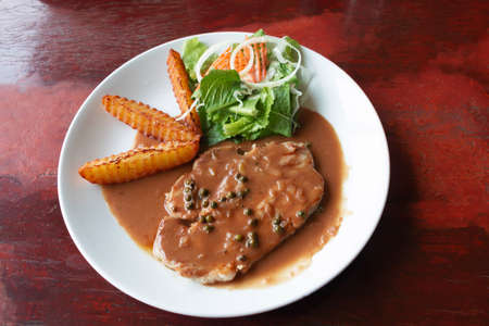 top view of pork chop steak on white plate with french fries and saladの写真素材