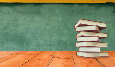 books on perspective wooden counter over blurred blackboard in classの写真素材